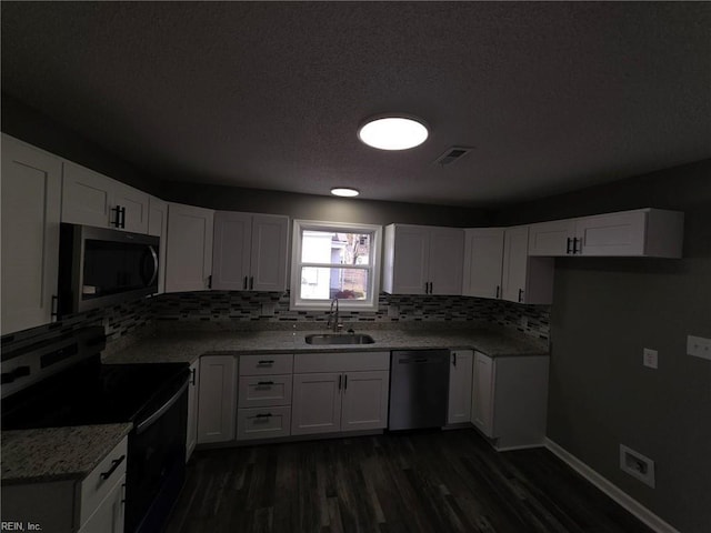 kitchen featuring electric range oven, dishwashing machine, stainless steel microwave, white cabinetry, and a sink