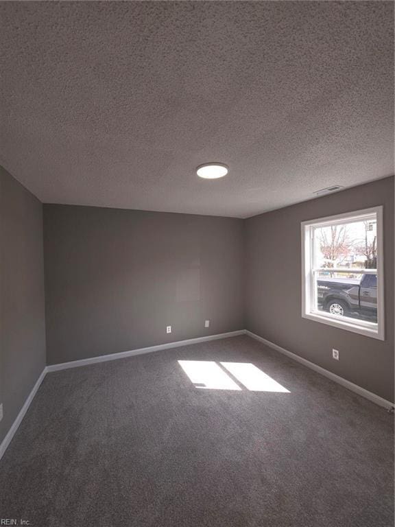 carpeted empty room with visible vents, baseboards, and a textured ceiling