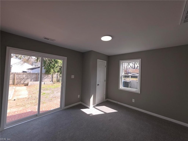 unfurnished room featuring dark colored carpet, visible vents, and baseboards