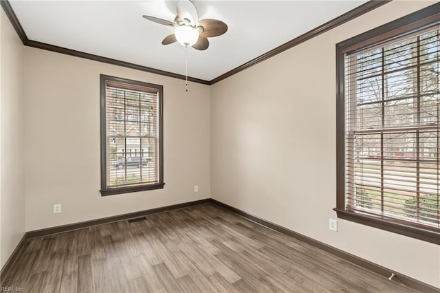 unfurnished room featuring crown molding, wood finished floors, visible vents, and baseboards