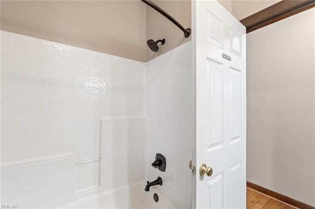 full bath featuring shower / washtub combination, baseboards, and wood finished floors