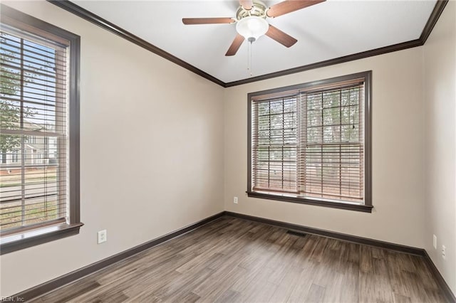 unfurnished room with baseboards, wood finished floors, visible vents, and crown molding