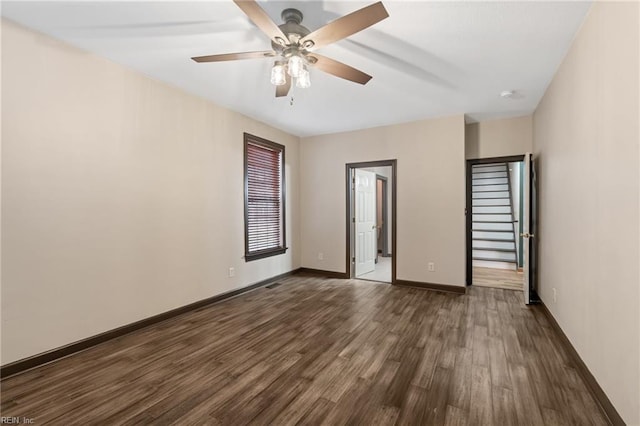 unfurnished room with dark wood-style flooring, ceiling fan, and baseboards