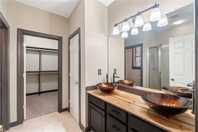 bathroom featuring double vanity, a stall shower, a sink, and visible vents