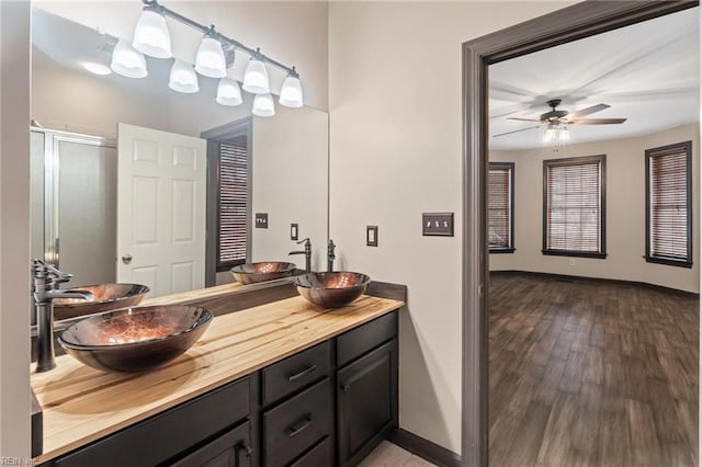 bathroom with wood finished floors, a stall shower, a sink, and baseboards