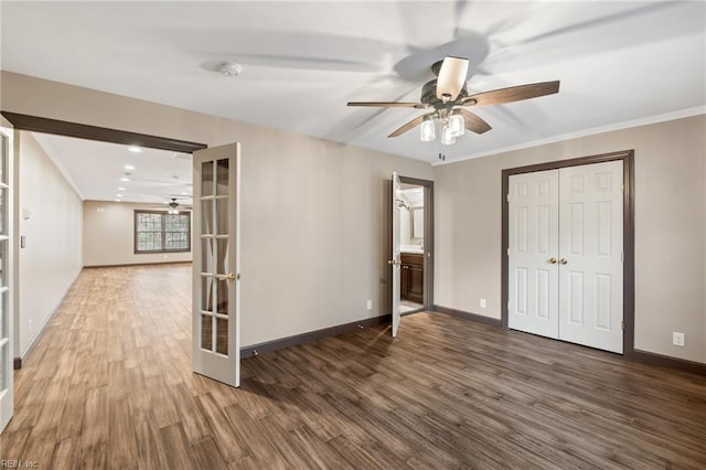 unfurnished room with baseboards, ornamental molding, wood finished floors, and french doors