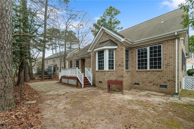 view of front facade featuring a deck, brick siding, crawl space, and a shingled roof