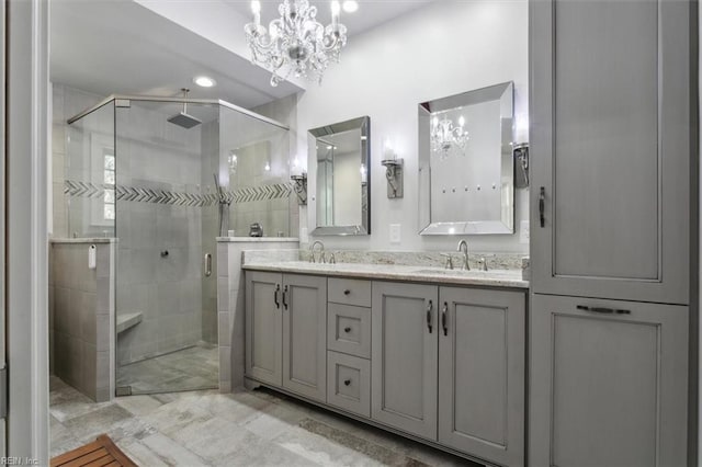 full bath with a chandelier, double vanity, a sink, and a shower stall