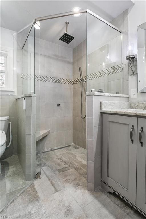 full bath featuring toilet, tiled shower, and vanity