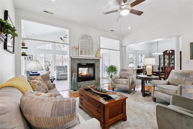 living area with a fireplace, decorative columns, visible vents, and a ceiling fan