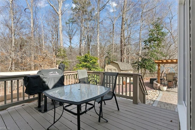 deck featuring a storage unit, outdoor dining area, and an outbuilding