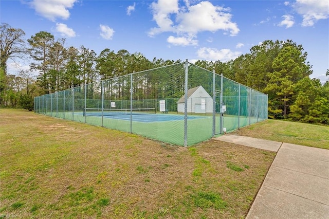 view of tennis court with fence and a yard