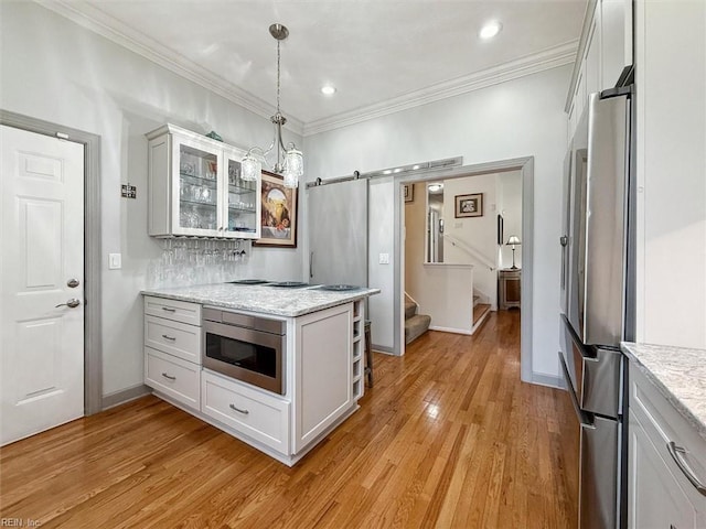 kitchen with a barn door, light wood-style flooring, freestanding refrigerator, built in microwave, and glass insert cabinets