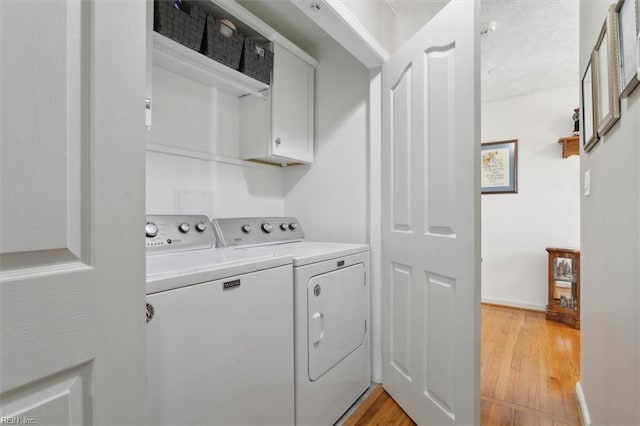 laundry room featuring cabinet space, independent washer and dryer, and light wood-style flooring