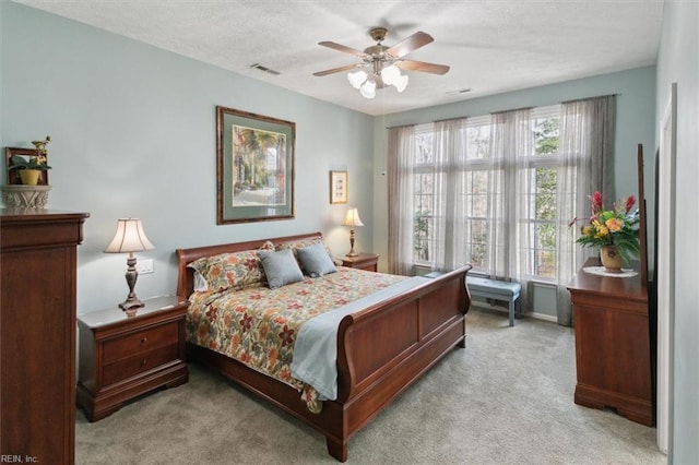 bedroom featuring carpet floors, ceiling fan, visible vents, and a textured ceiling