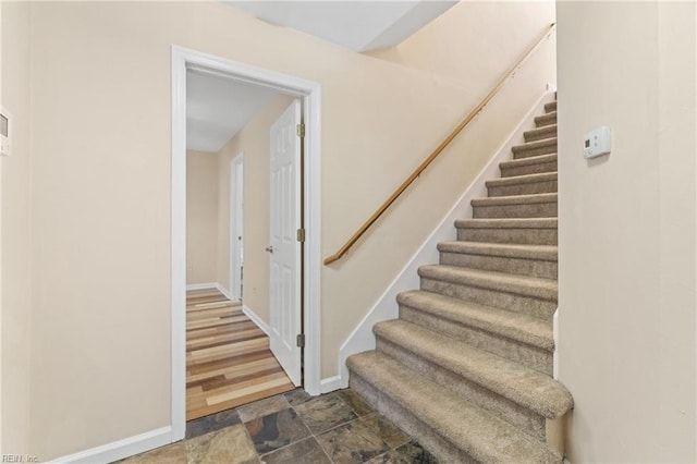 stairs featuring stone finish floor and baseboards