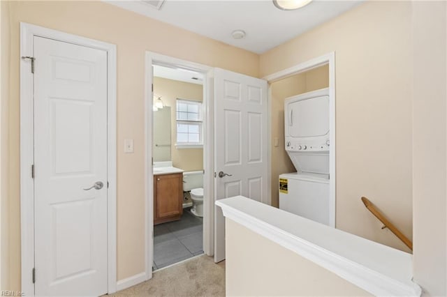 corridor with stacked washer and dryer, an upstairs landing, and light colored carpet