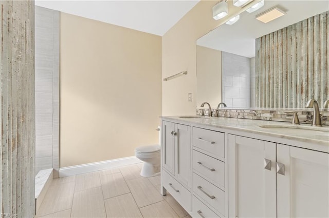 full bathroom featuring toilet, double vanity, baseboards, and a sink