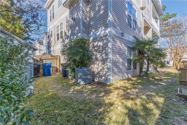 view of property exterior featuring a lawn, fence, and central air condition unit