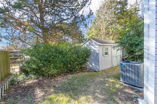 view of yard with an outbuilding, central AC, fence, and a storage unit