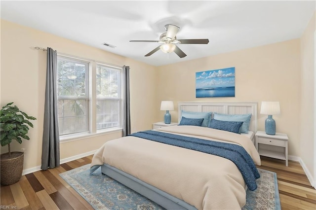 bedroom featuring ceiling fan, wood finished floors, visible vents, and baseboards