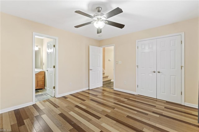 unfurnished bedroom with a closet, ensuite bath, light wood-style flooring, and baseboards