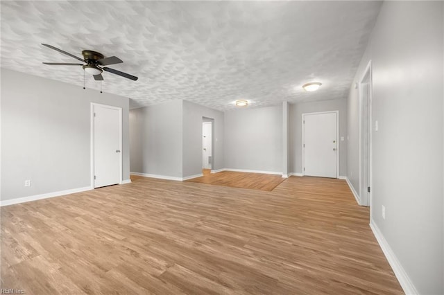 empty room with light wood-type flooring, a textured ceiling, and baseboards