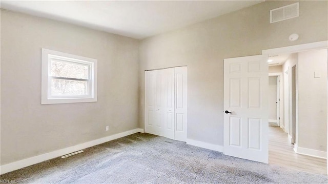 unfurnished bedroom with a closet, carpet flooring, visible vents, and baseboards