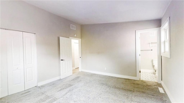 unfurnished bedroom with a closet, visible vents, carpet flooring, connected bathroom, and baseboards