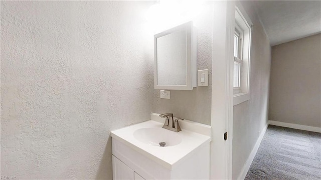 bathroom with a textured wall, vanity, and baseboards