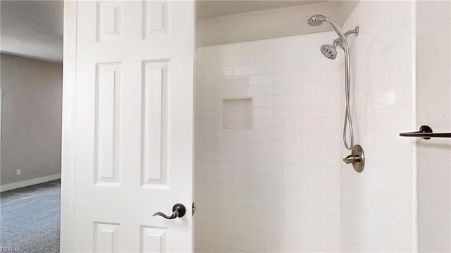 full bath with tiled shower and baseboards