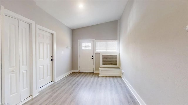 entrance foyer featuring light wood-style floors, vaulted ceiling, and baseboards