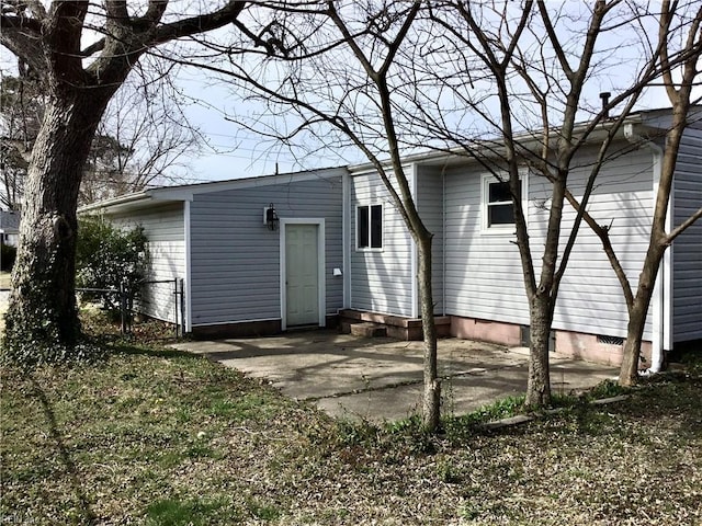 rear view of house with crawl space, a patio area, and fence