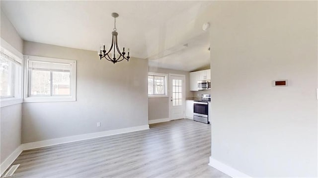 unfurnished dining area with light wood finished floors, baseboards, and a notable chandelier