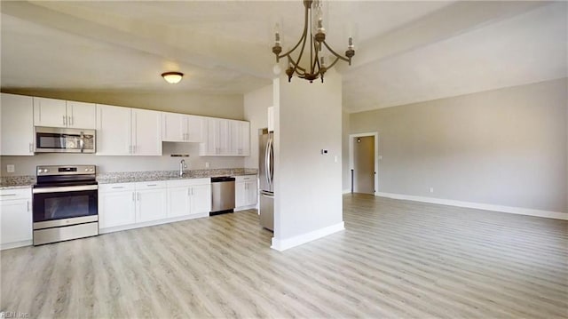 kitchen featuring baseboards, white cabinets, open floor plan, stainless steel appliances, and light wood-style floors