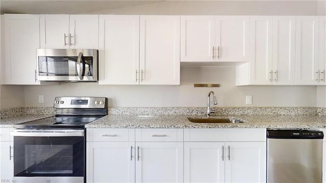 kitchen featuring appliances with stainless steel finishes, white cabinetry, and a sink