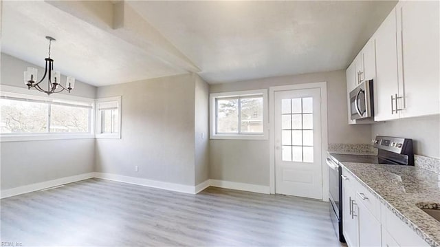 kitchen with appliances with stainless steel finishes, white cabinets, light stone countertops, light wood-type flooring, and baseboards