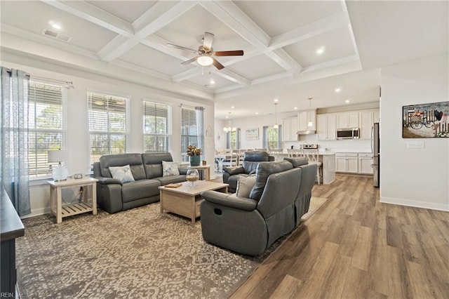 living area with light wood finished floors, plenty of natural light, coffered ceiling, and visible vents