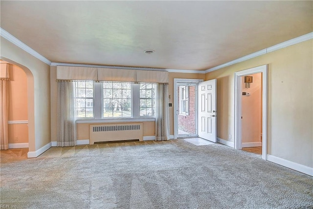 carpeted spare room with arched walkways, crown molding, baseboards, and radiator