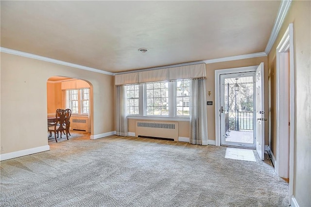 interior space with arched walkways, carpet flooring, visible vents, ornamental molding, and radiator