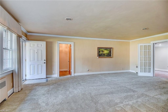 unfurnished room with carpet floors, crown molding, radiator, visible vents, and baseboards