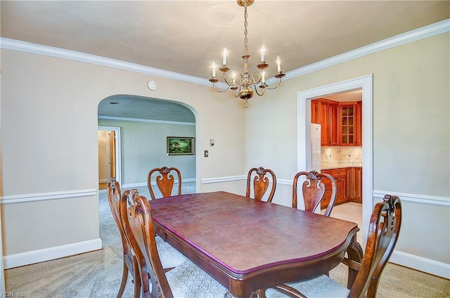 dining space with an inviting chandelier, baseboards, arched walkways, and crown molding