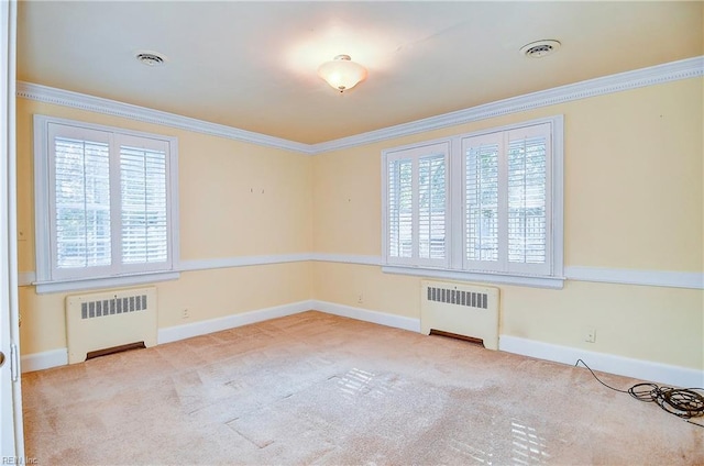 empty room with baseboards, visible vents, crown molding, and radiator heating unit