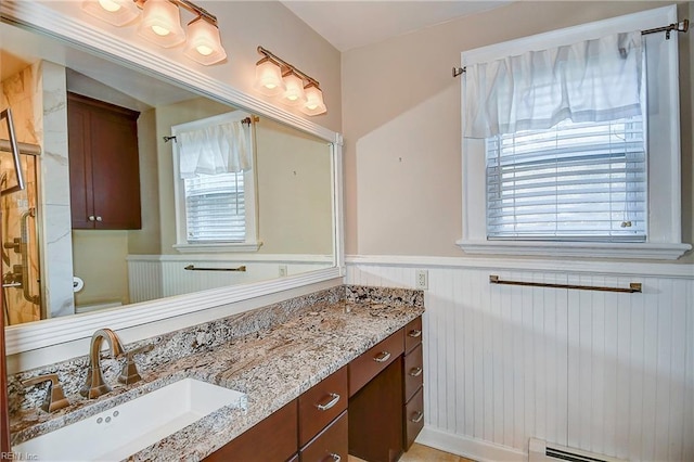 bathroom featuring toilet, a wainscoted wall, baseboard heating, and vanity