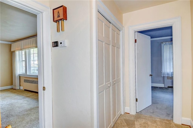 hall featuring radiator heating unit, crown molding, baseboards, and carpet flooring