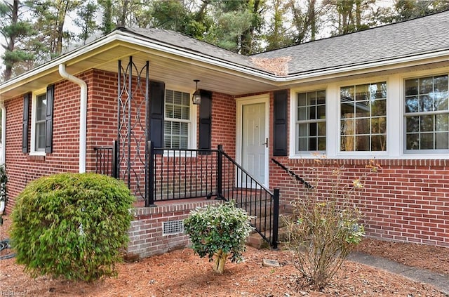 view of front of house featuring roof with shingles, brick siding, and crawl space