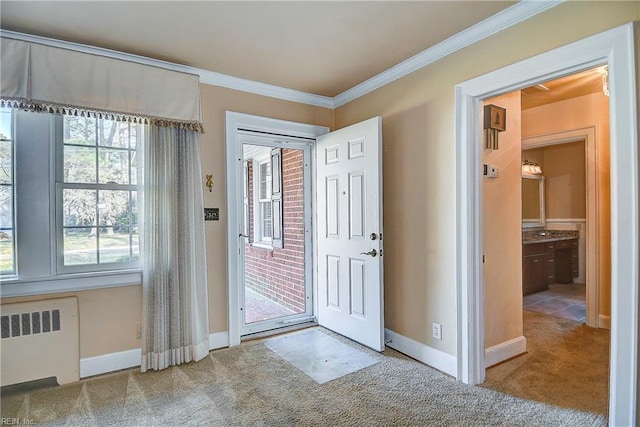 carpeted entryway with ornamental molding, radiator, and baseboards