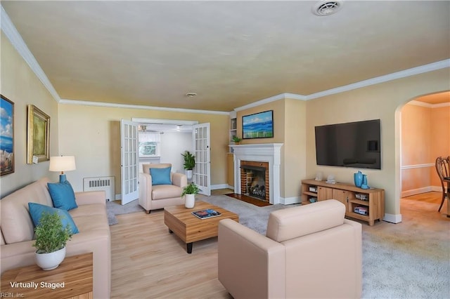 living room with visible vents, arched walkways, radiator, a fireplace with flush hearth, and french doors