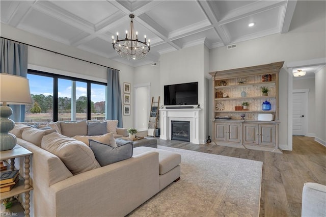 living room with a glass covered fireplace, coffered ceiling, wood finished floors, and a towering ceiling