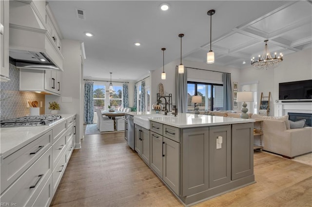 kitchen with custom range hood, visible vents, gray cabinetry, a sink, and coffered ceiling